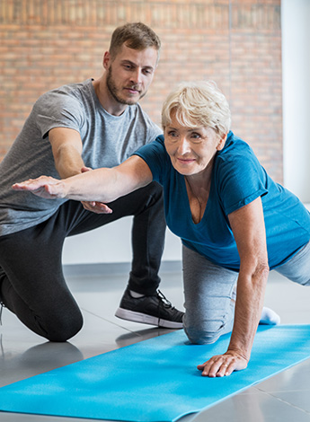 person on a yoga mat exercising with another person assisting